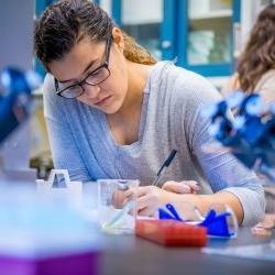 Student in laboratory taking notes around equipment